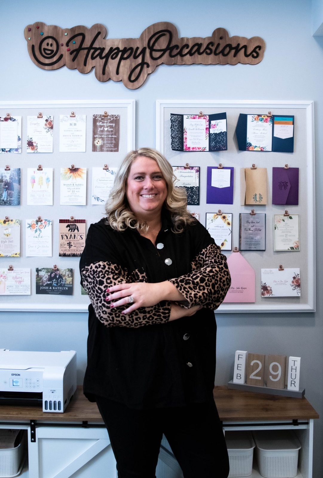 Owner, Amy Beth Williamson standing in front of Invitation Wall in Canton, Ohio